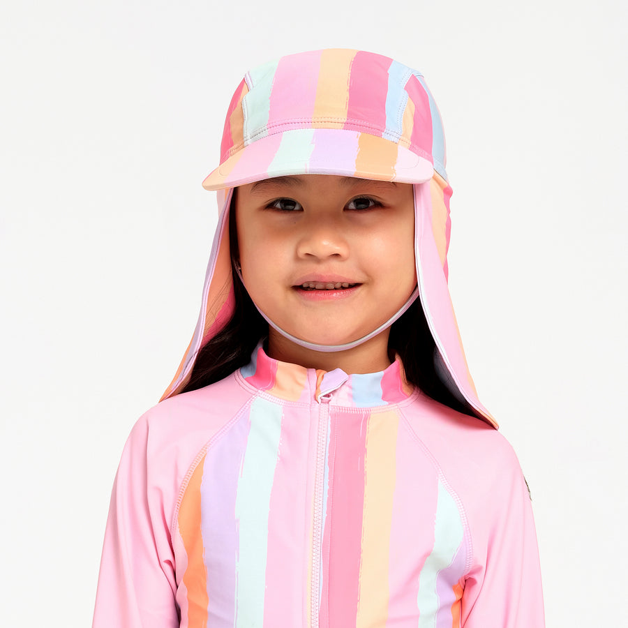 A young child wearing a pink striped sun hat with a neck flap and a matching pink striped long-sleeve swimsuit, photographed against a clean white background.