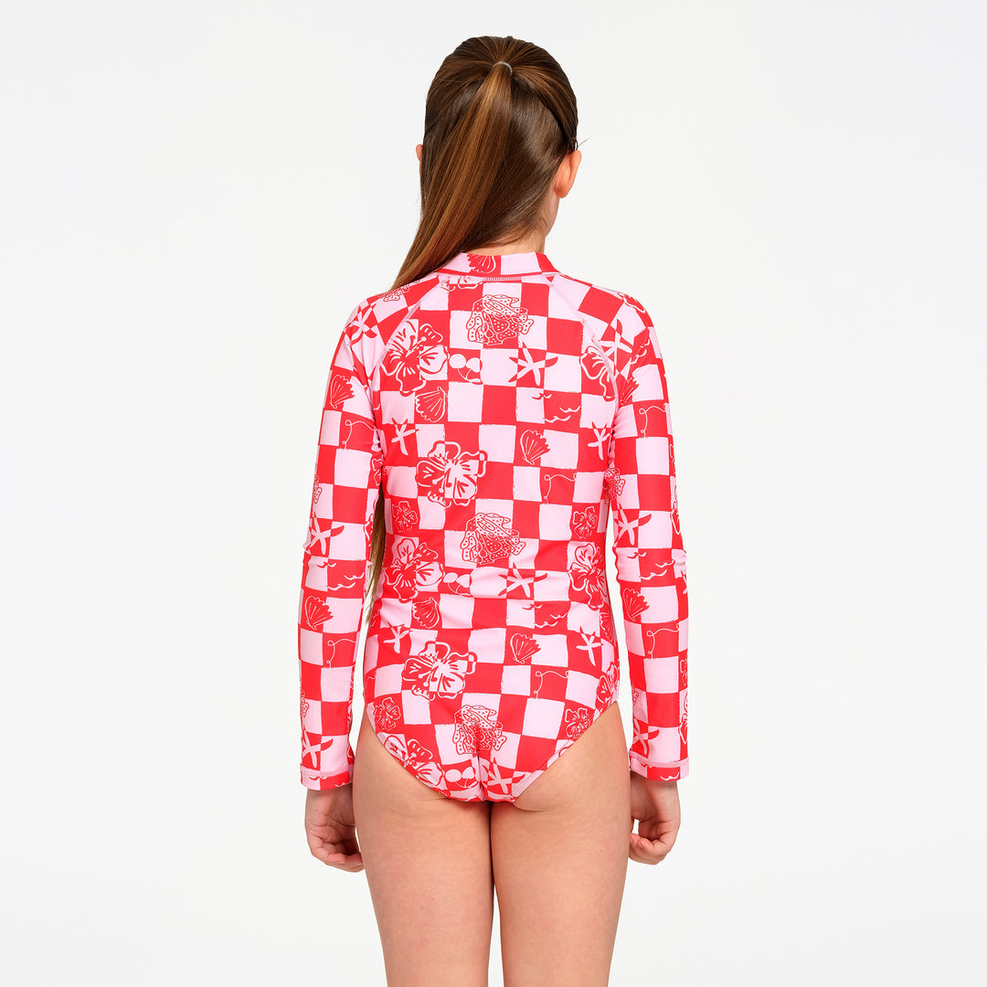 A girl viewed from the back wearing a red and white patterned long-sleeve swim leotard against a plain white background.