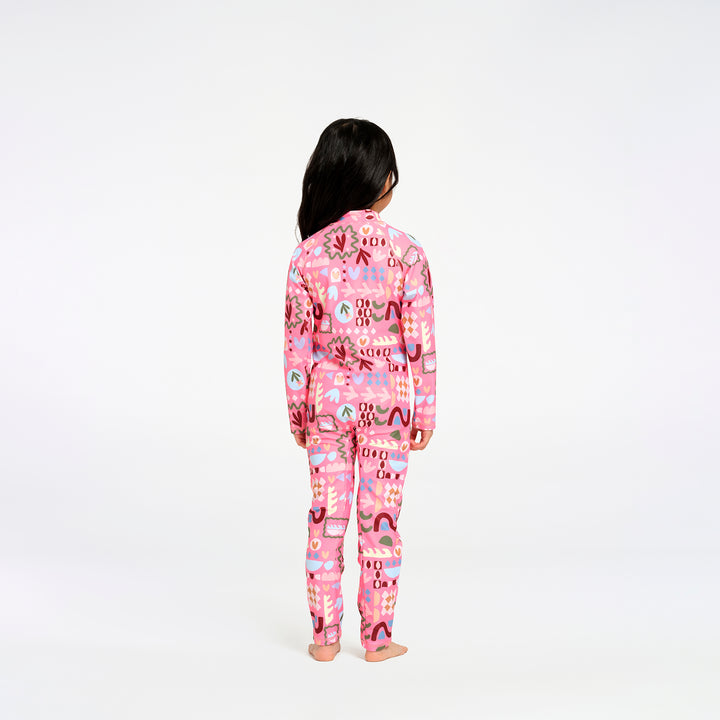 A child standing with their back to the camera, wearing a pink long-sleeve swimsuit with a colorful abstract pattern, photographed against a seamless white background.