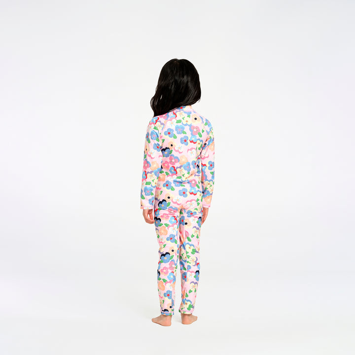 A child standing with their back to the camera, wearing a long-sleeve swimsuit with a colorful floral pattern on a white background.