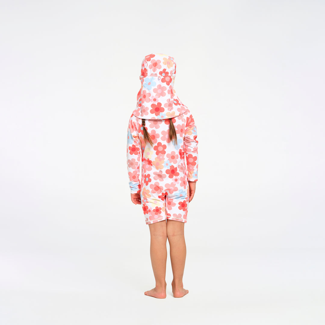 A child standing with their back to the camera, wearing a one-piece swimsuit and matching swim hat with a pink, red, and light blue floral pattern on a white background.