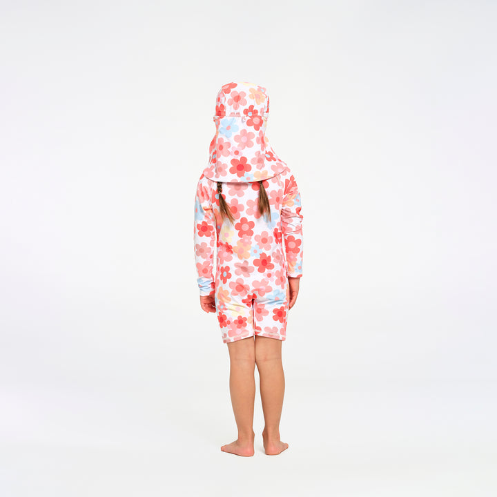 A child standing with their back to the camera, wearing a one-piece swimsuit and matching swim hat with a pink, red, and light blue floral pattern on a white background.