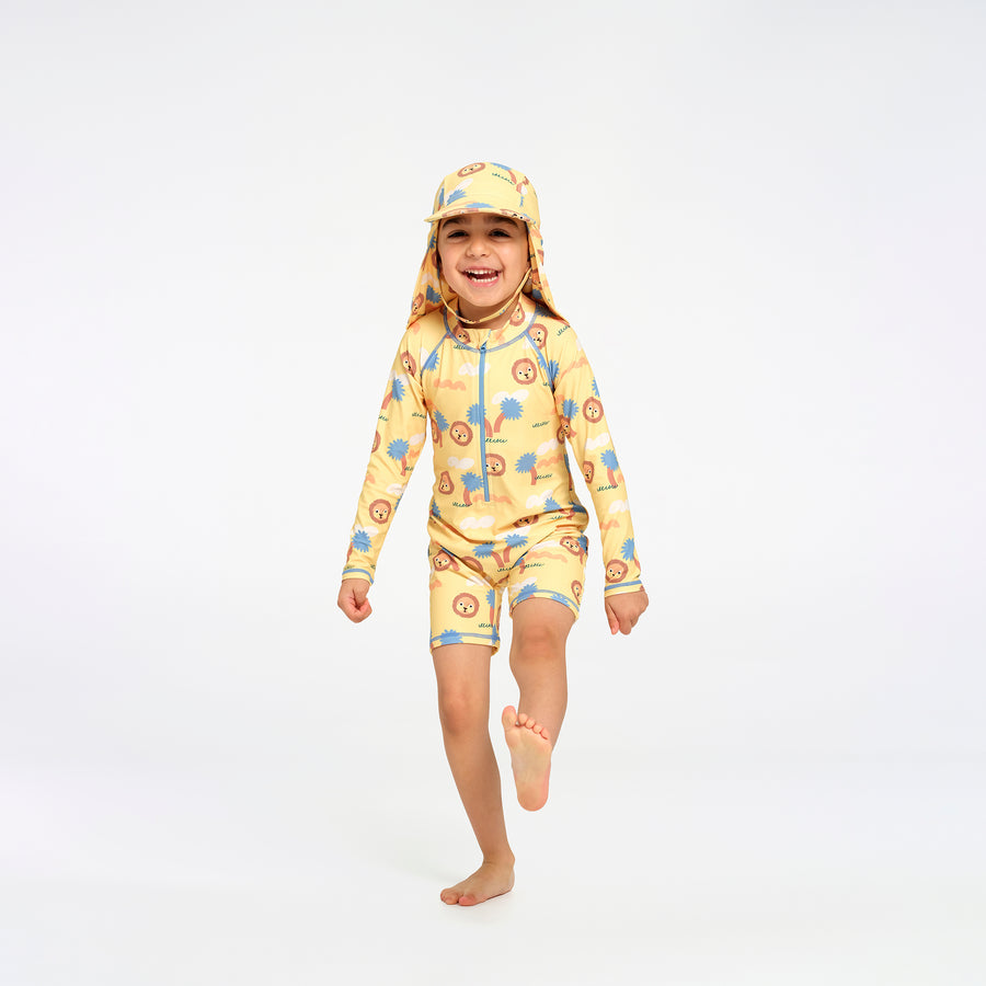 A young child wearing a yellow one-piece swimsuit and matching hat with a blue and orange jungle pattern, running barefoot on a white studio background.