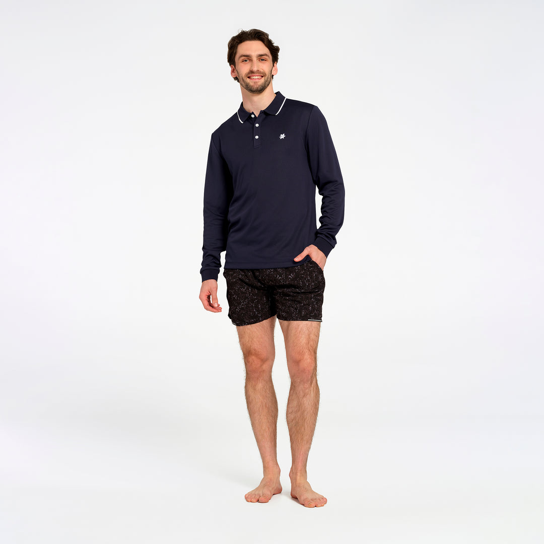 A man modeling a navy blue long-sleeve polo shirt with white trim and black patterned boxer briefs, standing against a plain white studio background.