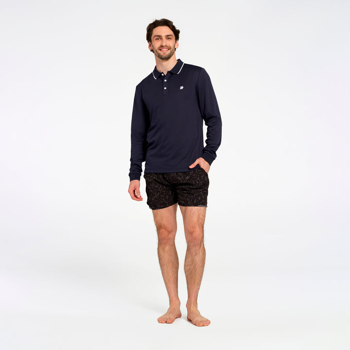 A man modeling a navy blue long-sleeve polo shirt with white trim and black patterned boxer briefs, standing against a plain white studio background.