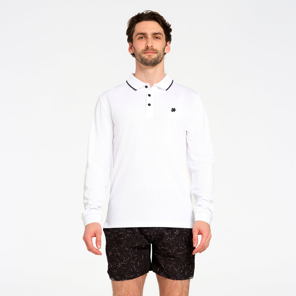 A man modeling a white long-sleeve polo shirt with a black embroidered logo on the left chest, paired with black patterned shorts, against a plain white background.