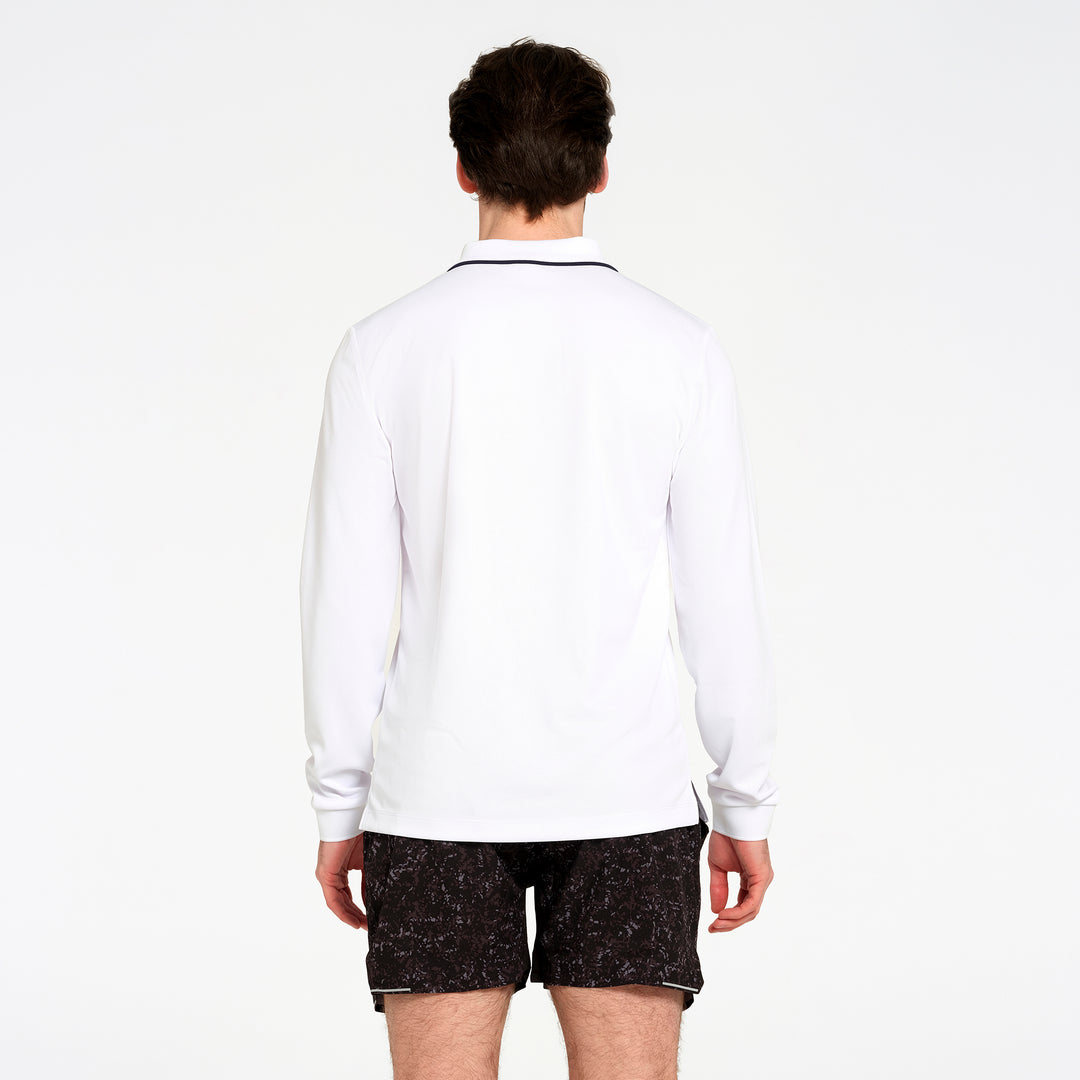 A man viewed from behind wearing a white long-sleeve athletic shirt with a thin black collar trim and black patterned shorts, against a plain white studio background.