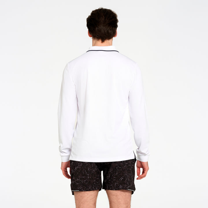 A man viewed from behind wearing a white long-sleeve athletic shirt with a thin black collar trim and black patterned shorts, against a plain white studio background.