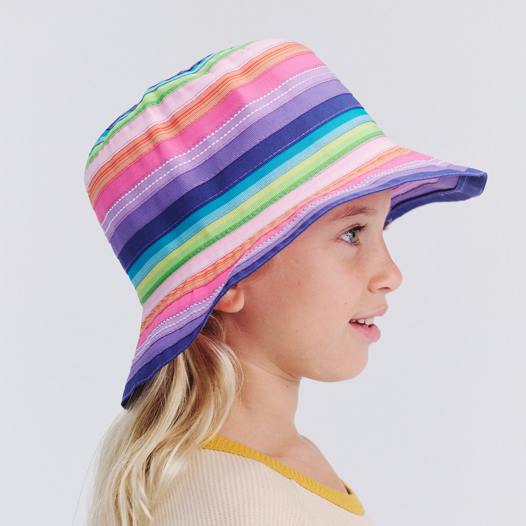 Child wearing a colorful striped bucket hat on a plain background
