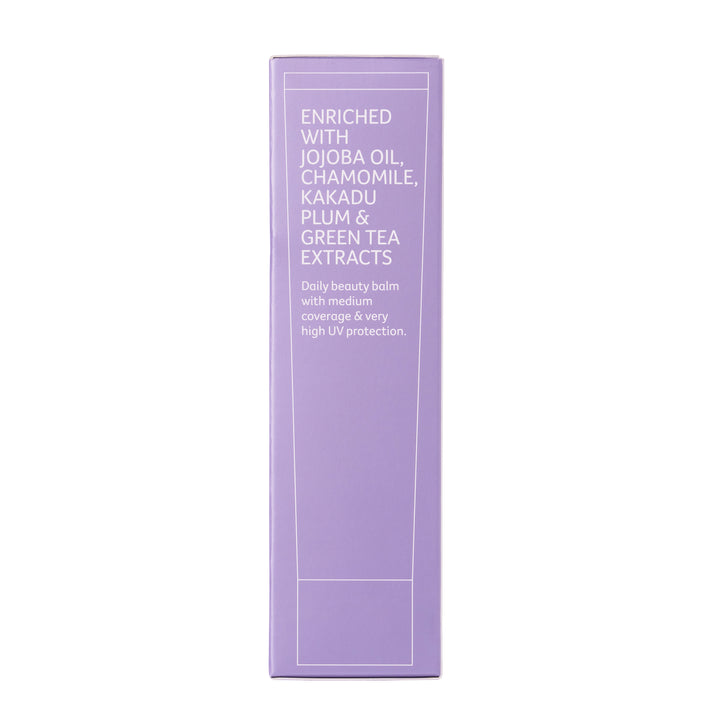 A tall, narrow lavender purple box for a beauty balm, featuring white text that lists ingredients like jojoba oil, chamomile, kakadu plum, and green tea extracts, set against a plain white background.