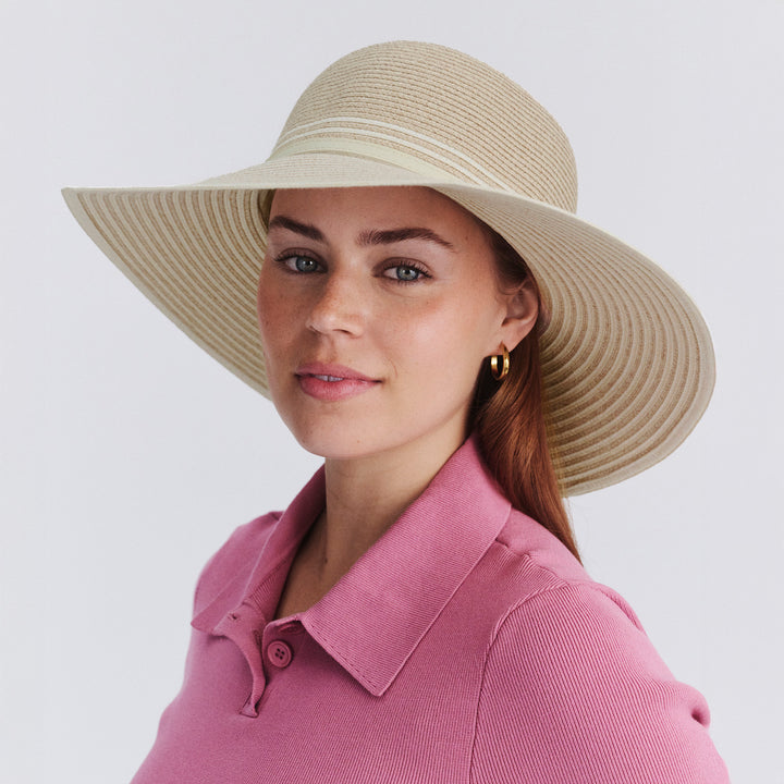 Female model wearing Amy Striped Capeline Hat in camel and ivory mix, three-quarter angle highlighting striped detail and flowing silhouette