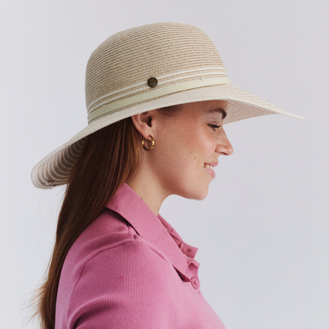 Female model wearing Amy Striped Capeline Hat in camel and ivory mix, side profile showing wide brim coverage and elegant style