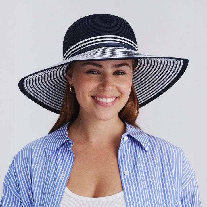 Female model wearing Amy Striped Capeline Hat in Navy/White colour, front view showcasing fit and wide brim