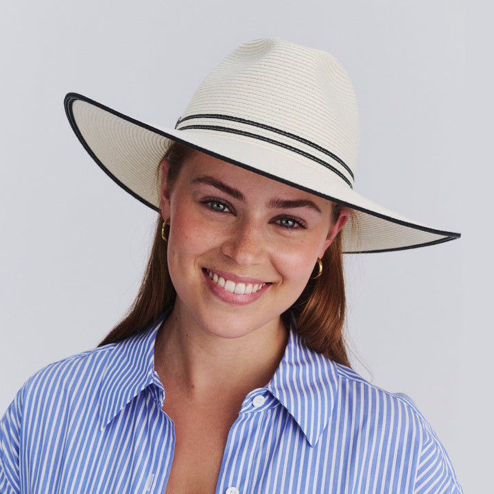 Female model wearing Liza Wide Brim Fedora Hat in Ivory/Black colour, three-quarter angle highlighting shape and silhouette