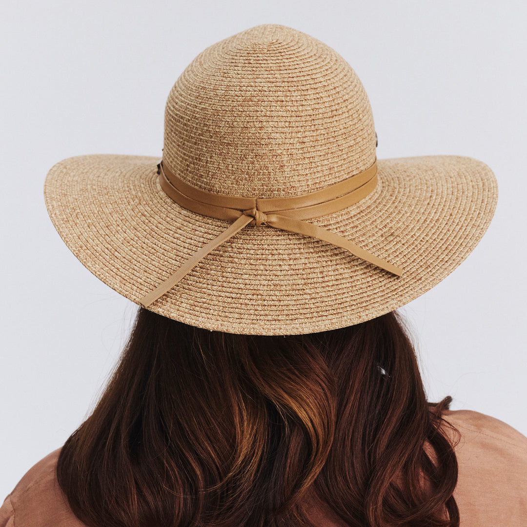Female model wearing Gena Capeline Hat in camel colour, back view showing crown shape, brim width, and trim tie detail