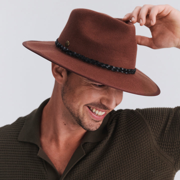 Male model wearing Bartle Fedora Hat in chocolate colour, hat tipped down showing brim detail