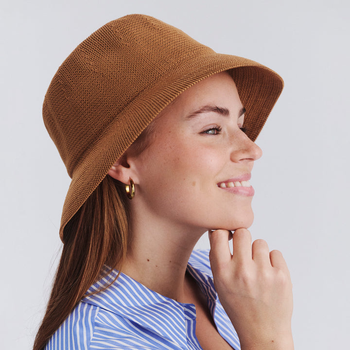 Female model wearing Tamzin Bucket Hat in biscuit colour, side profile showing brim coverage and shape