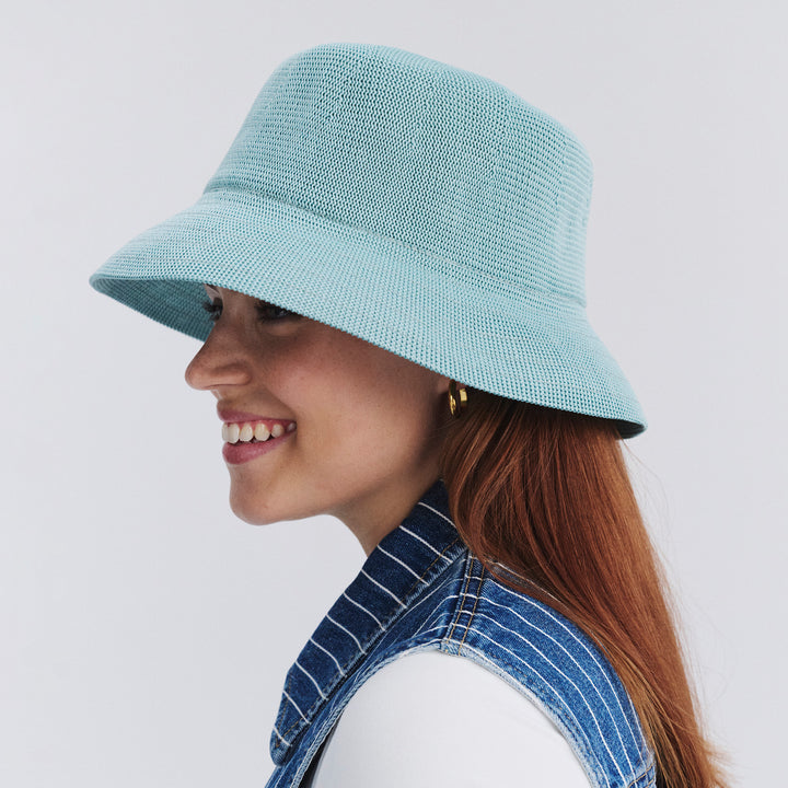 Female model wearing Tamzin Bucket Hat in blue haze colour, side profile showing brim coverage and shape