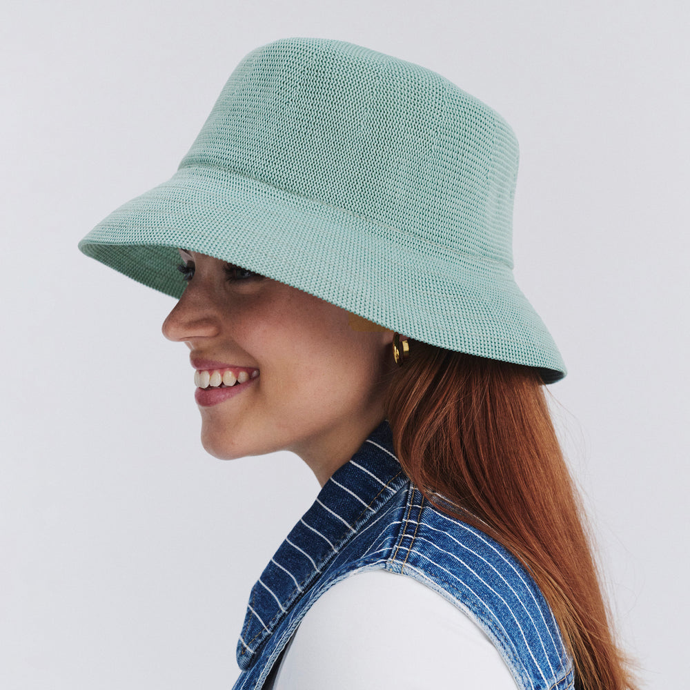 Female model wearing Tamzin Bucket Hat in blue haze colour, side profile showing brim coverage and shape