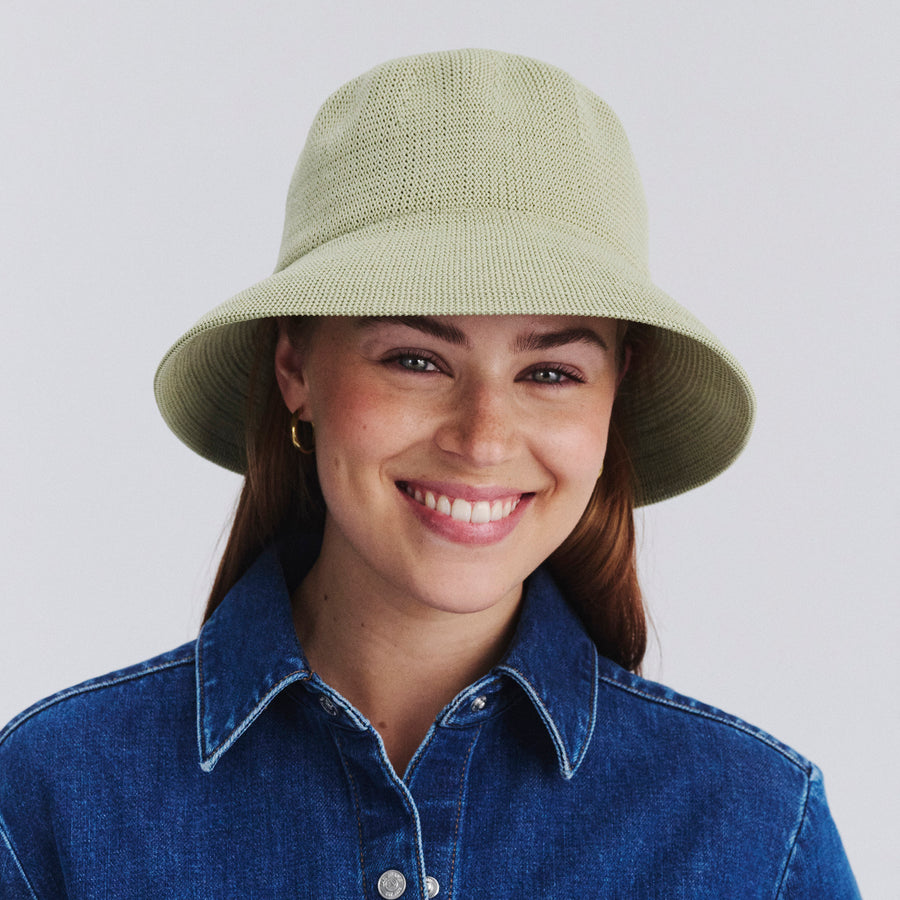 Female model wearing Tamzin Bucket Hat in light moss green colour, front view styled with denim outfit