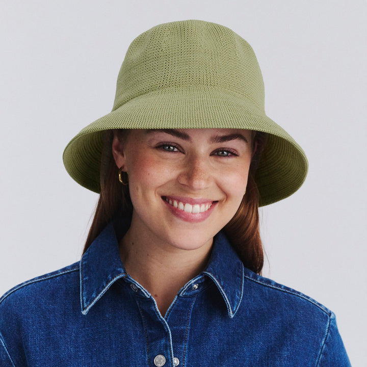 Female model wearing Tamzin Bucket Hat in light moss green colour, front view styled with denim outfit