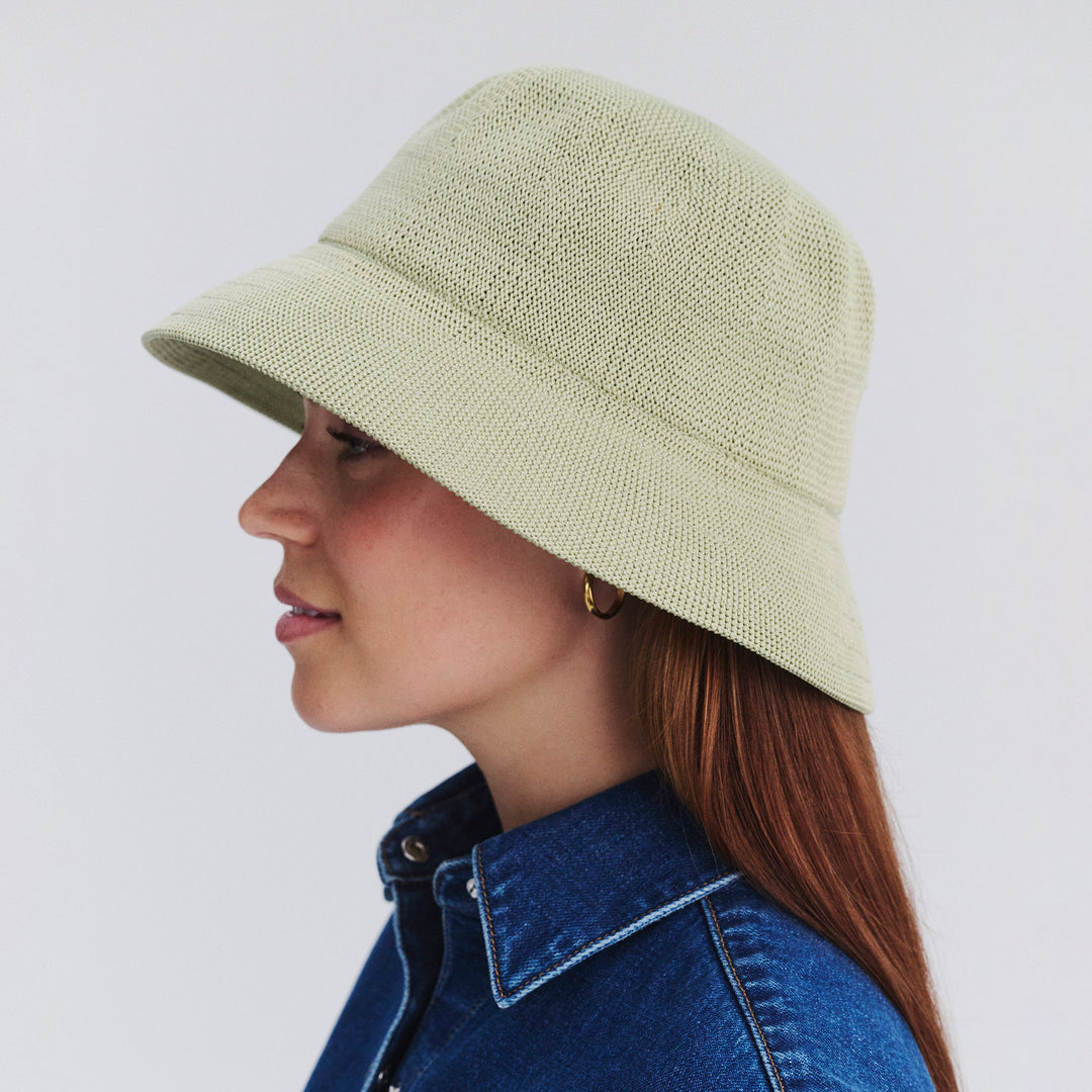 Female model wearing Tamzin Bucket Hat in light moss green colour, side profile showing brim coverage and shape