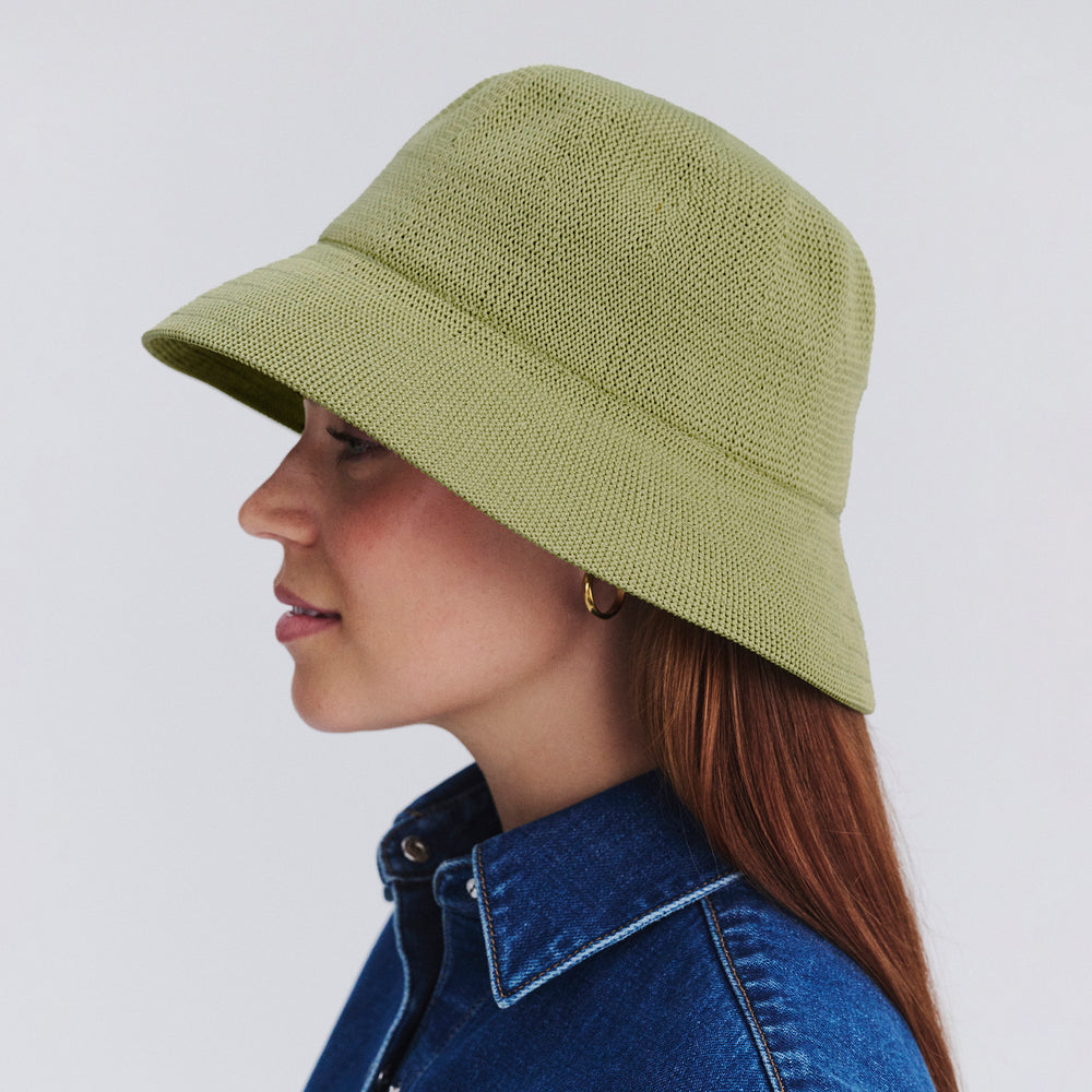 Female model wearing Tamzin Bucket Hat in light moss green colour, side profile showing brim coverage and shape