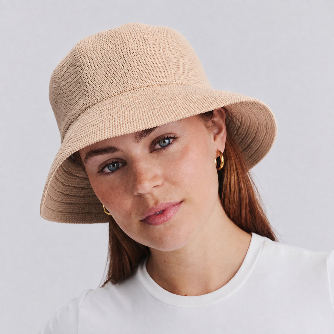 Female model wearing Tamzin Bucket Hat in beige colour, front view showcasing fit and sun-protective brim coverage