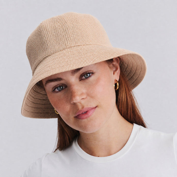 Female model wearing Tamzin Bucket Hat in beige colour, front view showcasing fit and sun-protective brim coverage