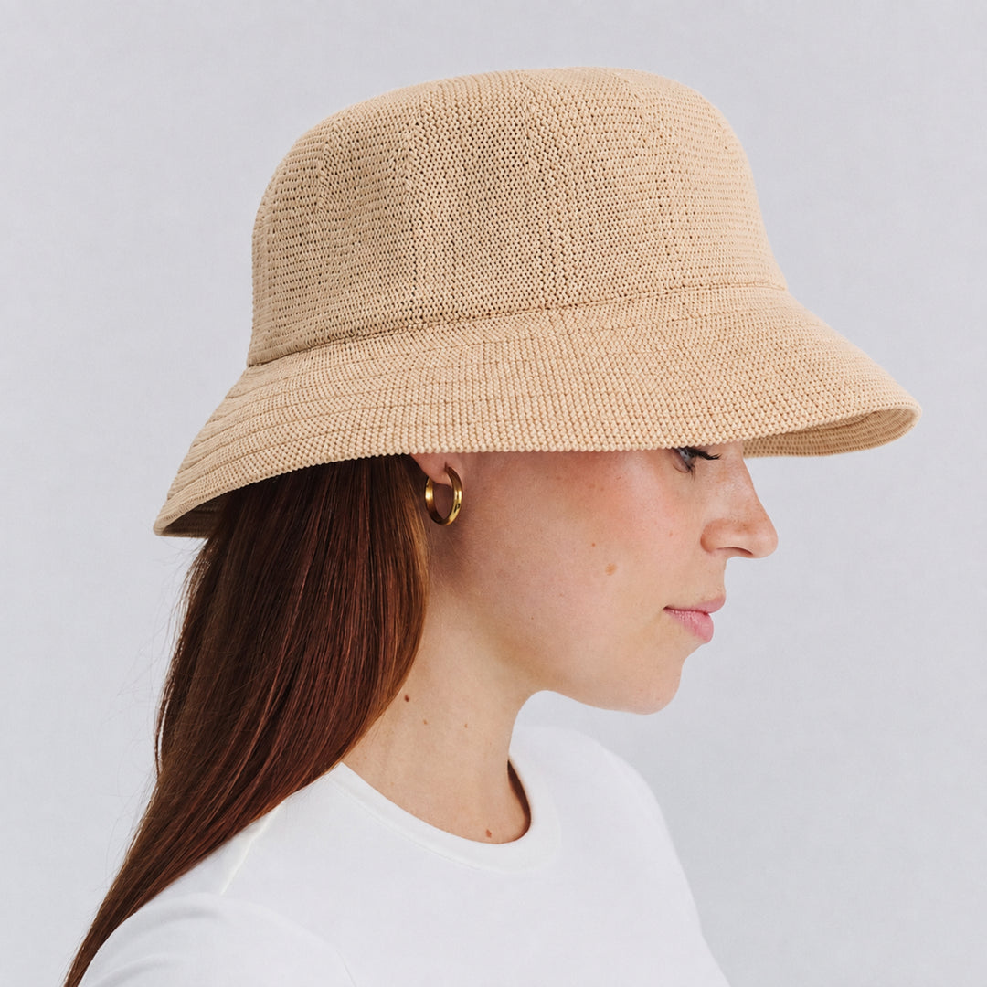 Female model wearing Tamzin Bucket Hat in beige colour, side profile showing relaxed silhouette and brim coverage