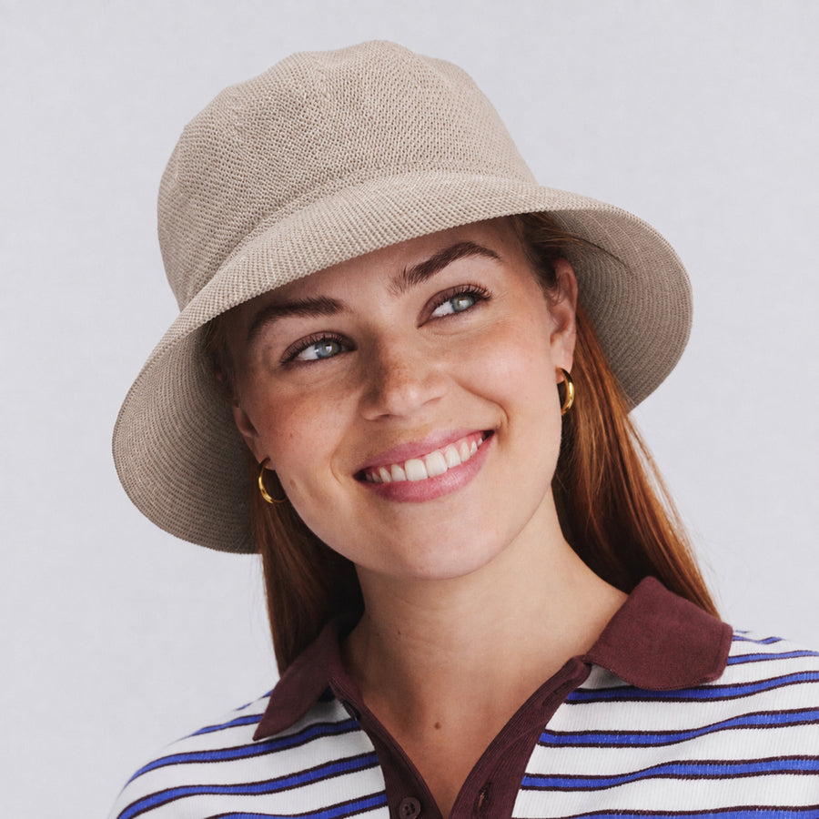 Female model wearing Tamzin Bucket Hat in stone colour, front view showcasing fit and sun-protective brim coverage
