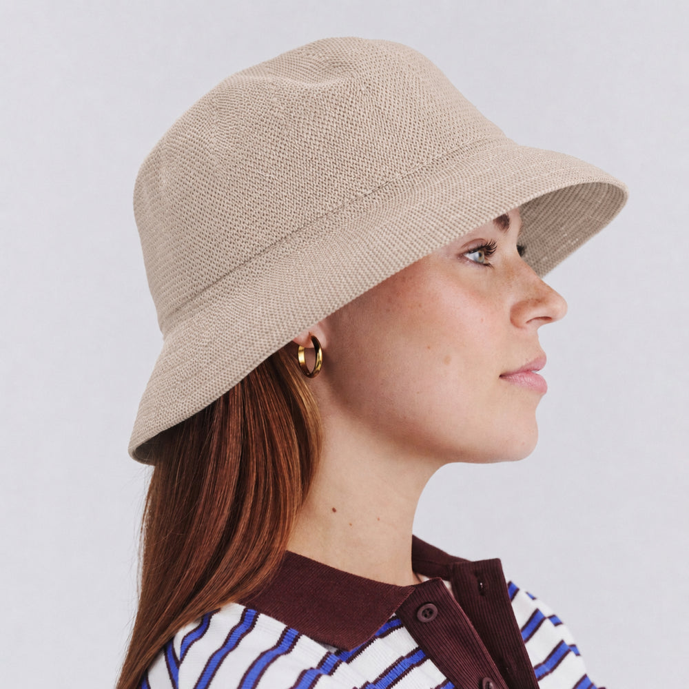 Female model wearing Tamzin Bucket Hat in stone colour, side profile showing relaxed silhouette and brim coverage