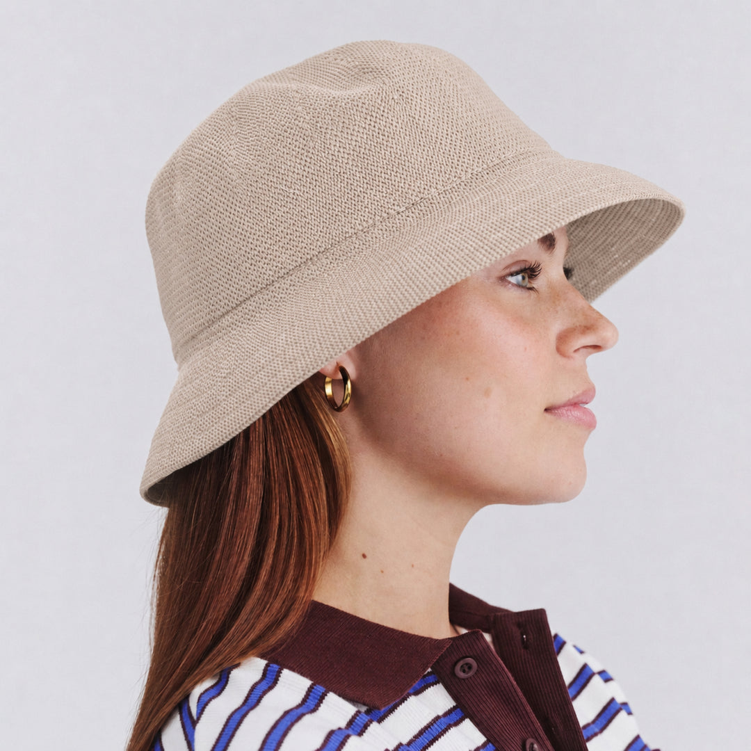 Female model wearing Tamzin Bucket Hat in stone colour, side profile showing relaxed silhouette and brim coverage