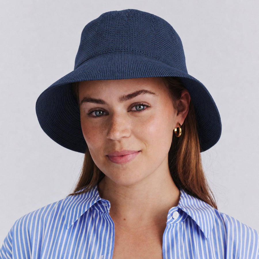 Female model wearing Tamzin Bucket Hat in navy colour, front view showcasing fit and sun-protective brim coverage