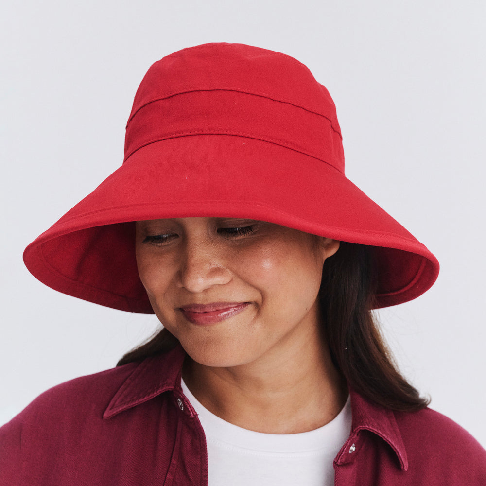 Female model wearing Essential Traveller Hat in poppy red colour with brim turned down