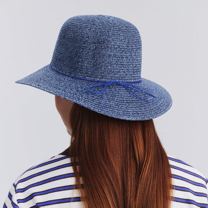 Back view of female model wearing Lacey bucket hat in Denim showing brim shape and rear detailing