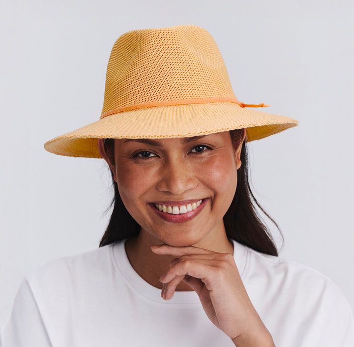 Female model wearing Jacqui Mannish Hat in Apricot colour, front view showcasing fit and wide brim