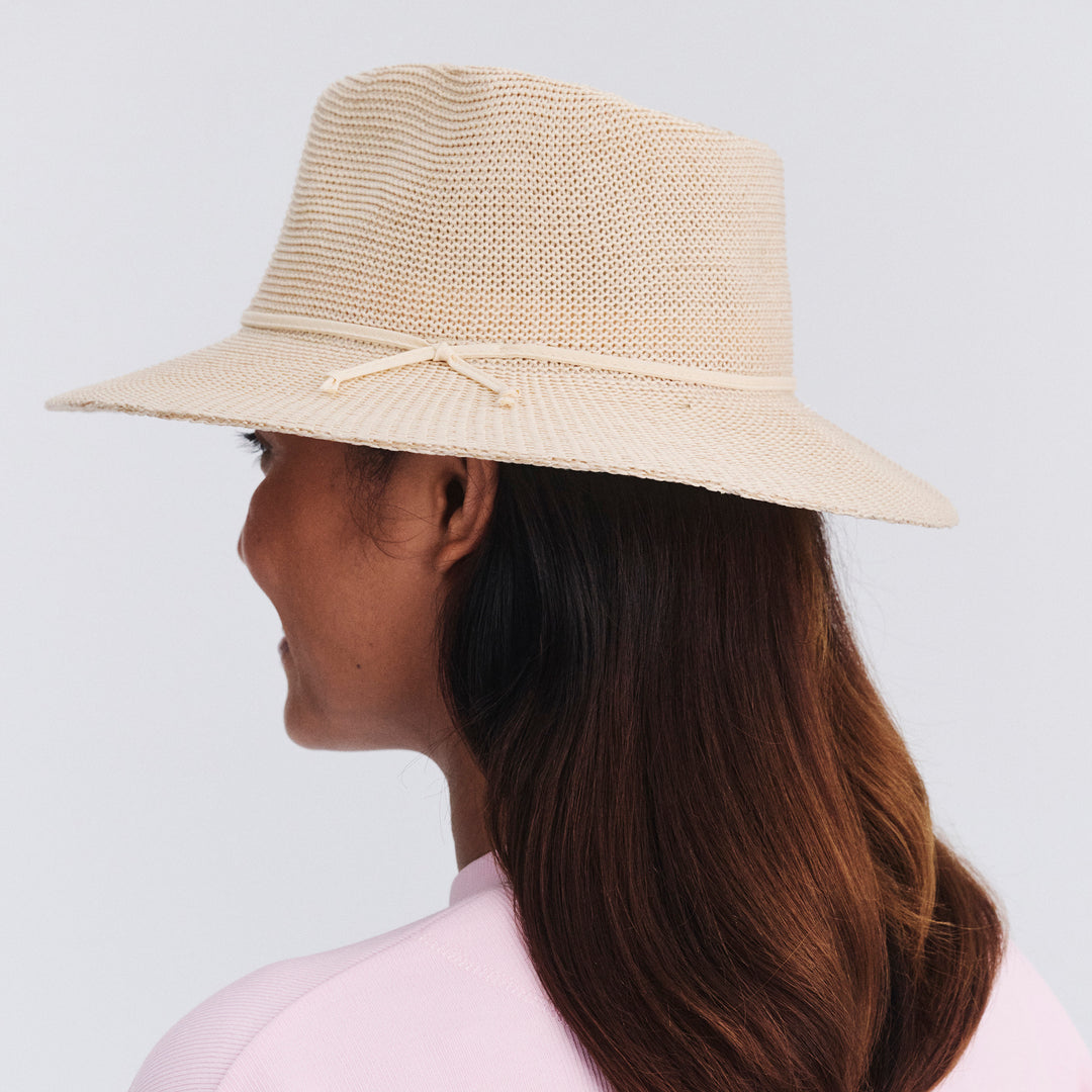 Back view of female model wearing Jacqui mannish hat in Beige showing brim shape and rear detailing