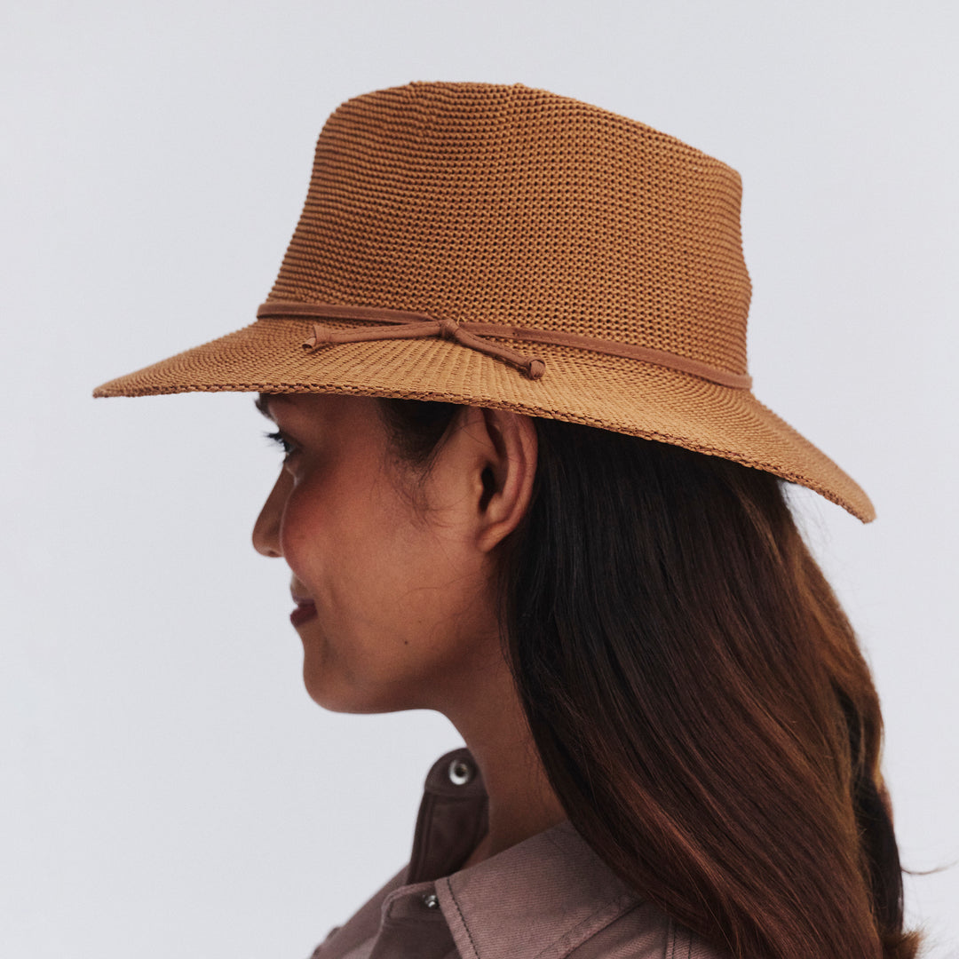 Female model wearing Jacqui Mannish Hat in biscuit colour, side profile showing structured shape and brim detail