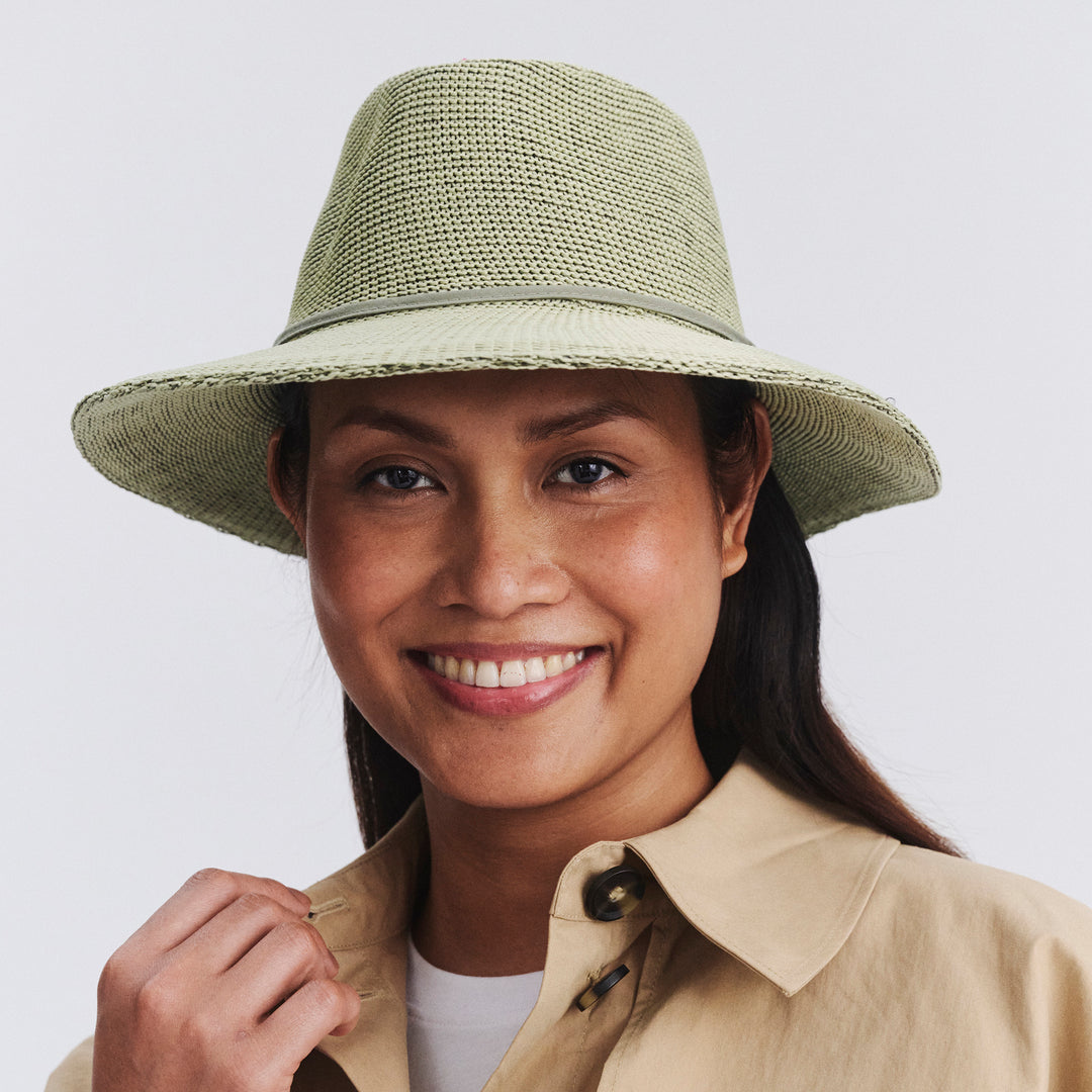 Female model wearing Jacqui Mannish Hat in light moss green colour, front view styled with beige shirt