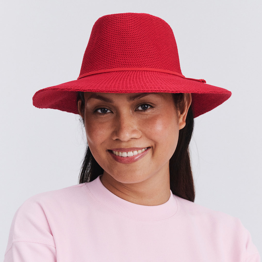 Female model wearing Jacqui Mannish Hat in red poppy colour, front view styled with pink top