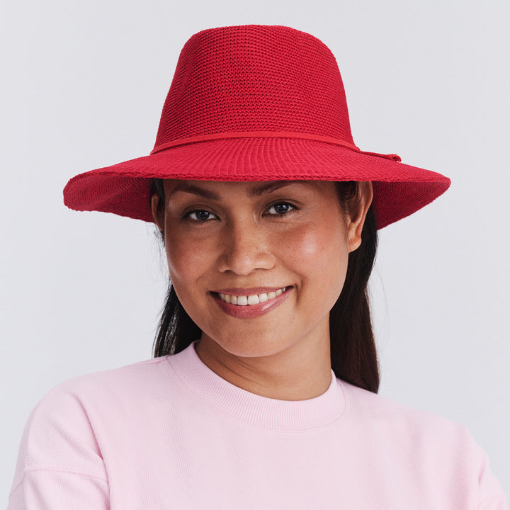 Female model wearing Jacqui Mannish Hat in red poppy colour, front view styled with pink top
