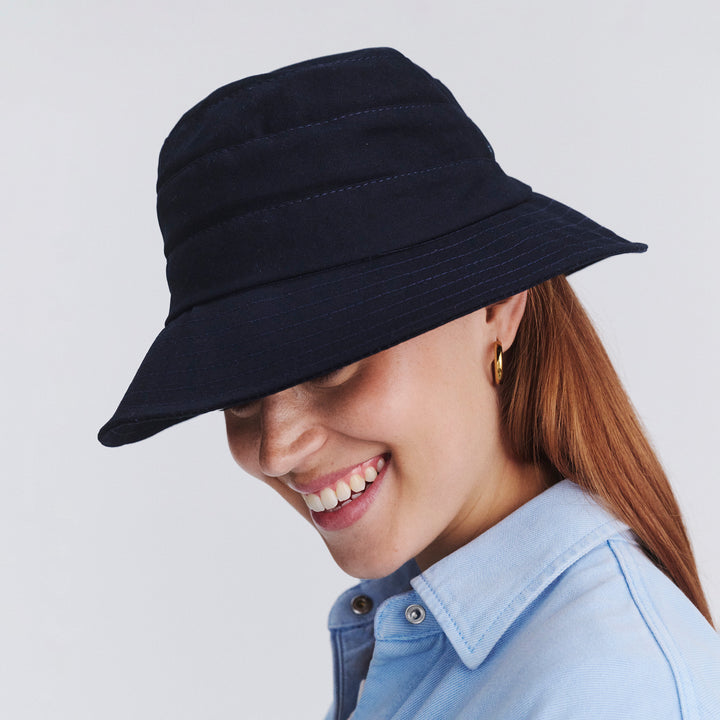 Female model wearing Golf bucket hat in Navy, front‑facing view with brim tipped down