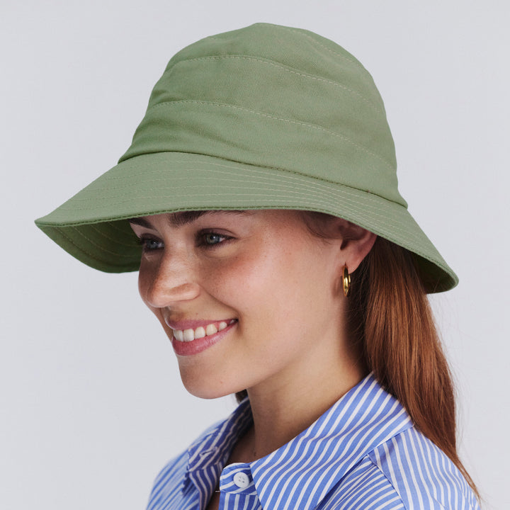 Female model wearing Golf Bucket Hat in sage colour, side profile showing brim coverage and silhouette