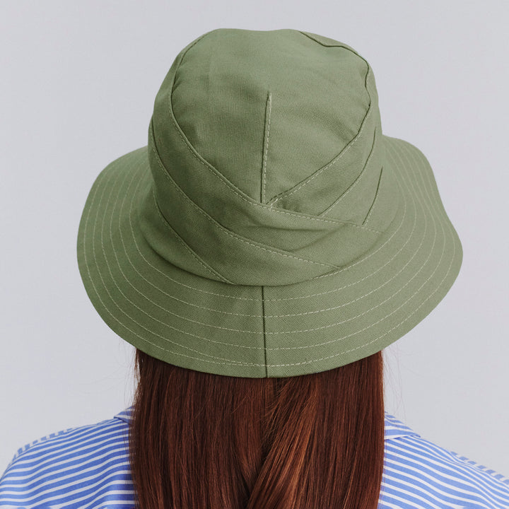Female model wearing Golf Bucket Hat in sage colour, back view showing crown fit and overall style