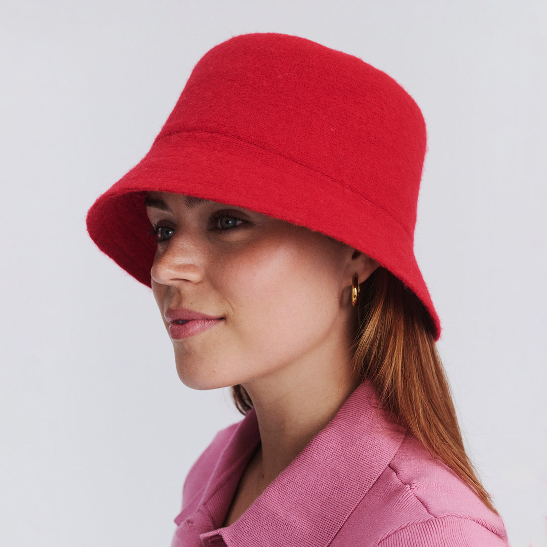 Female model wearing Isadora Bucket Hat in red colour, side profile showing brim coverage and shape