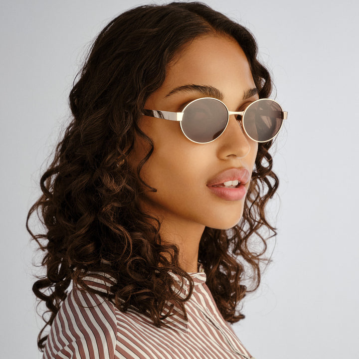 Female model wearing Norwood sunglasses in Gold, three‑quarter angle