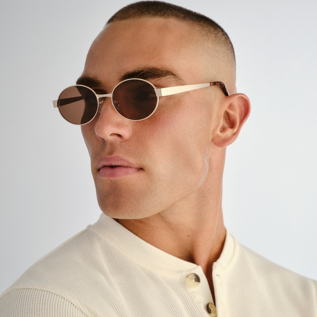 Male model wearing Norwood sunglasses in Gold, three‑quarter angle