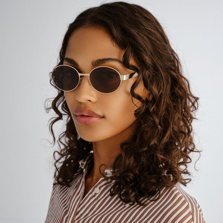 Front profile of female model wearing Norwood sunglasses in Gold
