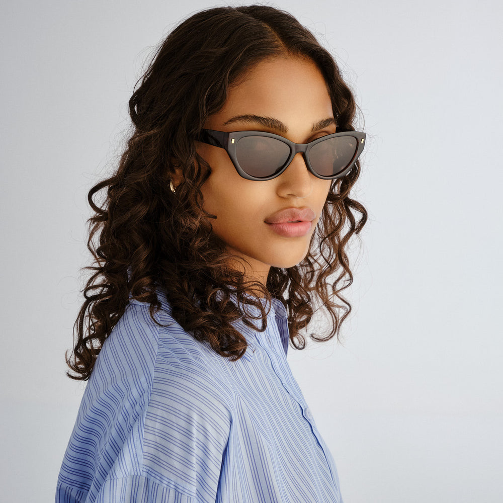 Female model wearing Swanbourne sunglasses in Rust, three‑quarter angle